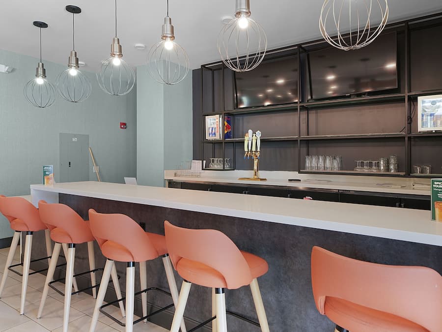 A modern bar area with a counter, bar stools, and overhead lighting.