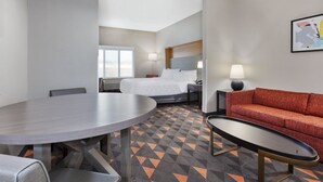 Una habitación de hotel con una cama, una mesa redonda de comedor, un sofá y una pequeña mesa.