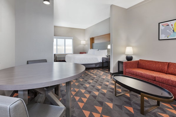 Une chambre d’hôtel comprenant un lit, une table de salle à manger ronde, un canapé et une petite table.