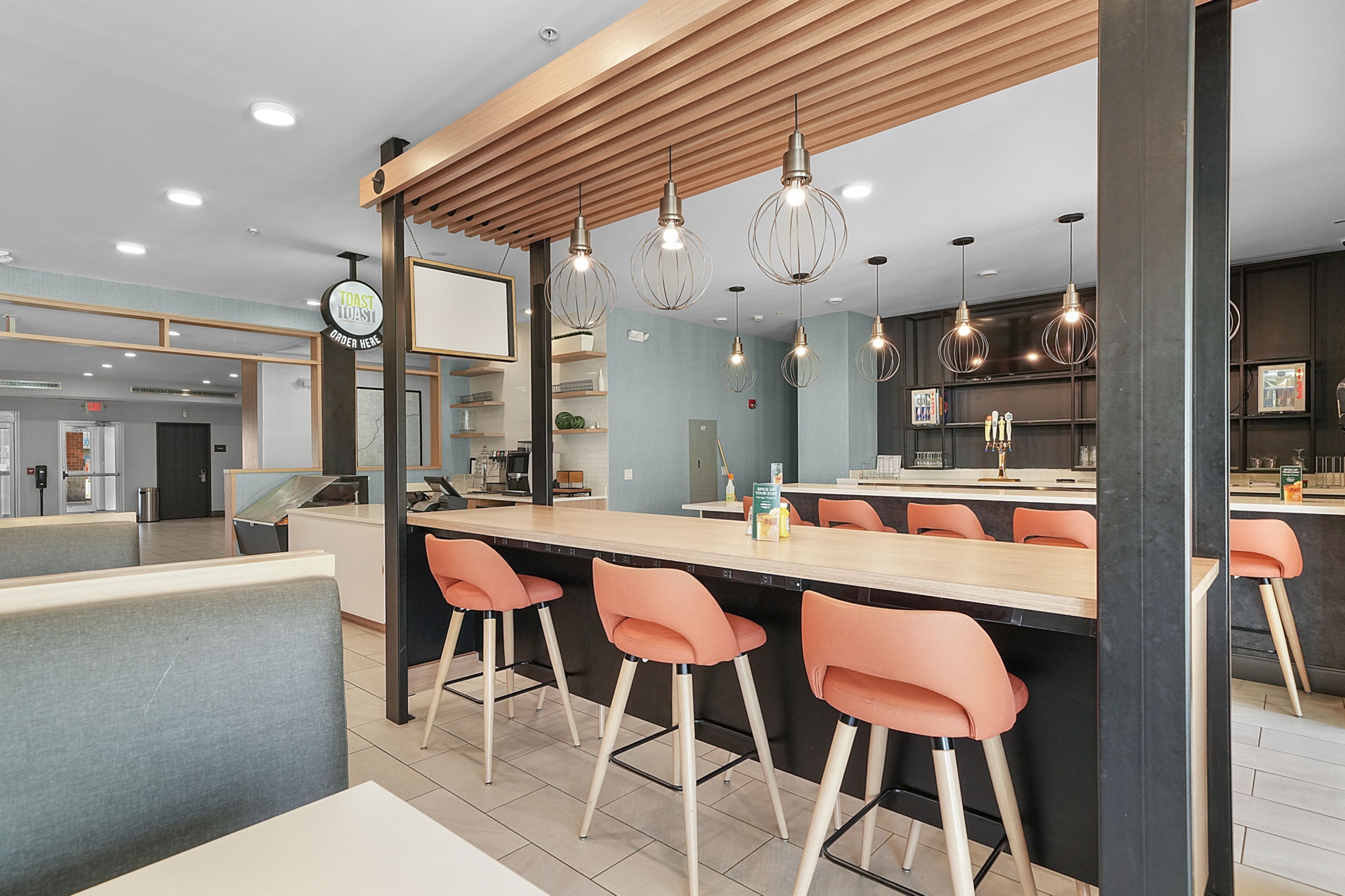 A modern bar area with a wooden ceiling, bar stools, and pendant lighting.