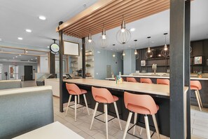 A modern bar area with a wooden ceiling, bar stools, and pendant lighting. - Holiday Inn Grand Rapids - South by IHG (Grand Rapids)