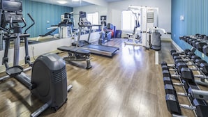 A gym with cardio machines, weight benches, and dumbbells.