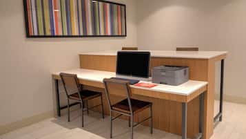 A modern office space with a desk, two chairs, a laptop, a printer, and a colorful abstract painting on the wall.