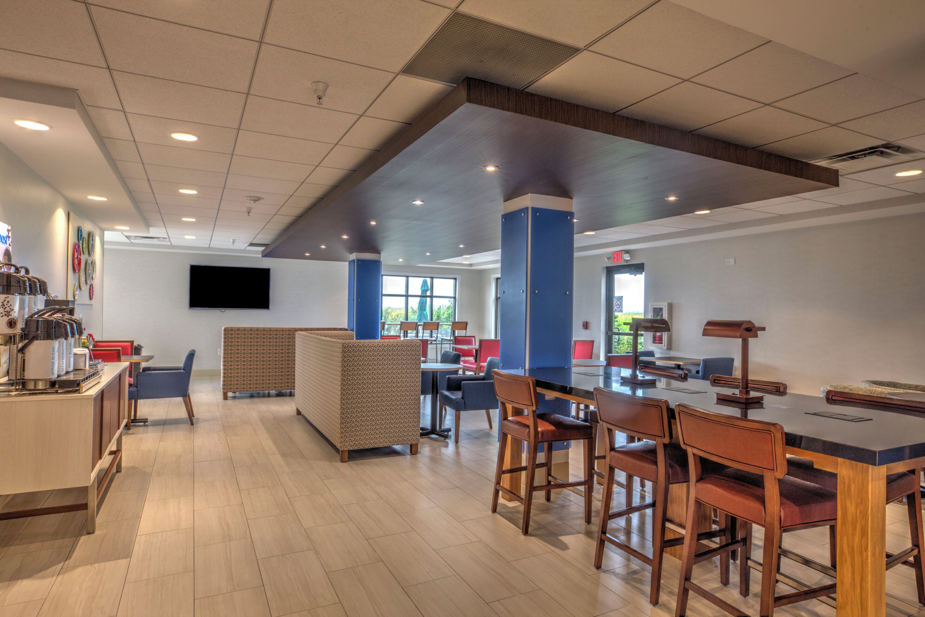 A modern cafe interior with a bar area, seating, and a flat-screen TV mounted on the wall.