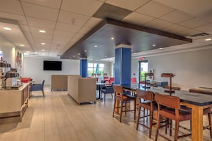 A modern cafe interior with a bar area, seating, and a flat-screen TV mounted on the wall. - Holiday Inn Express Rochelle by IHG (Rochelle)