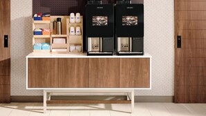 A coffee station with two coffee machines, a coffee grinder, and various coffee pods and containers. - Holiday Inn Express Rochelle by IHG (Rochelle)