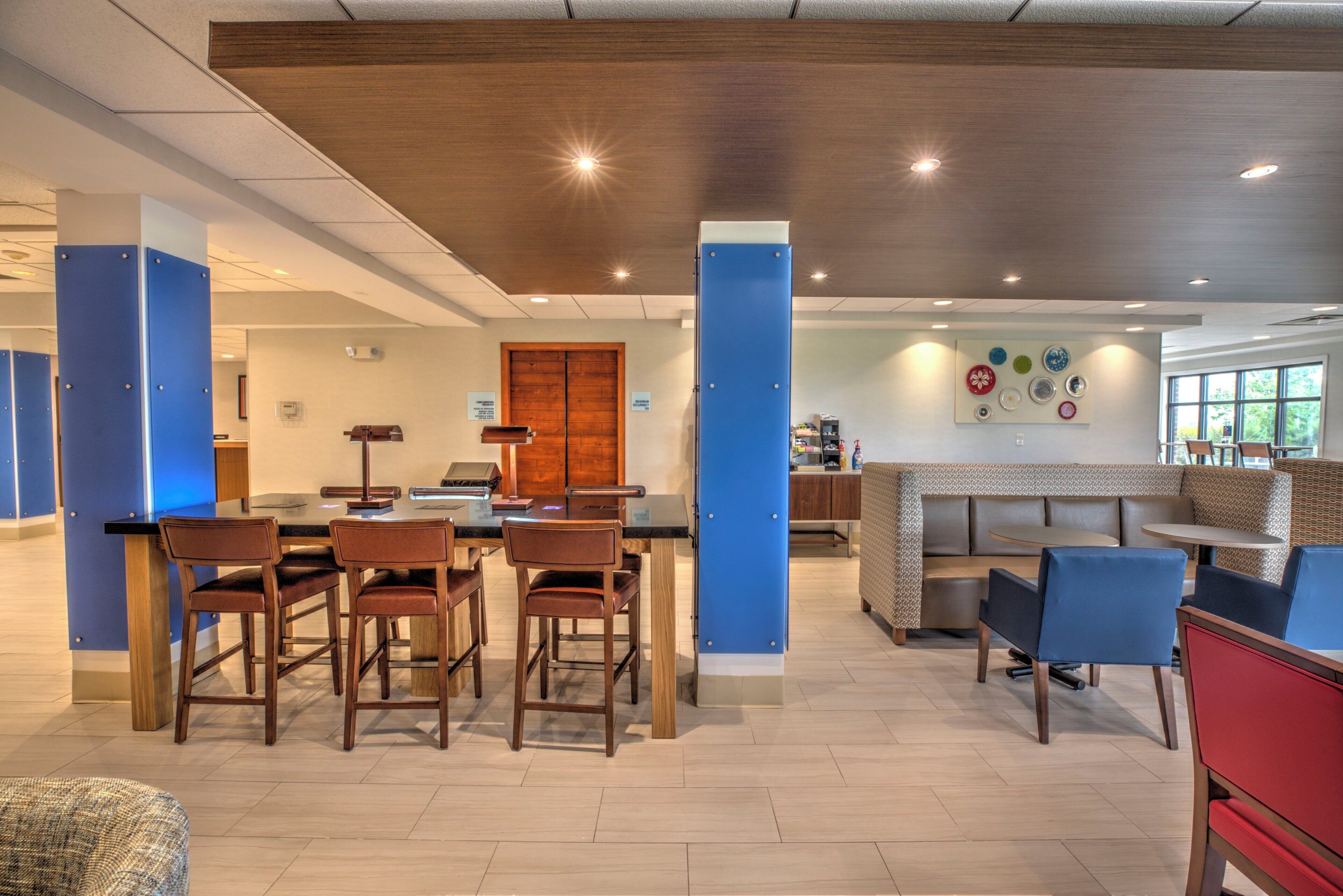A modern interior with a dining area, a reception desk, and a seating area with a patterned wall.