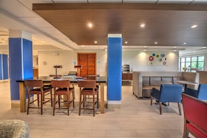 A modern interior with a dining area, a reception desk, and a seating area with a patterned wall. - Holiday Inn Express Rochelle by IHG (Rochelle)
