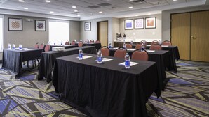A conference room with tables, chairs, water bottles, and a projector screen.