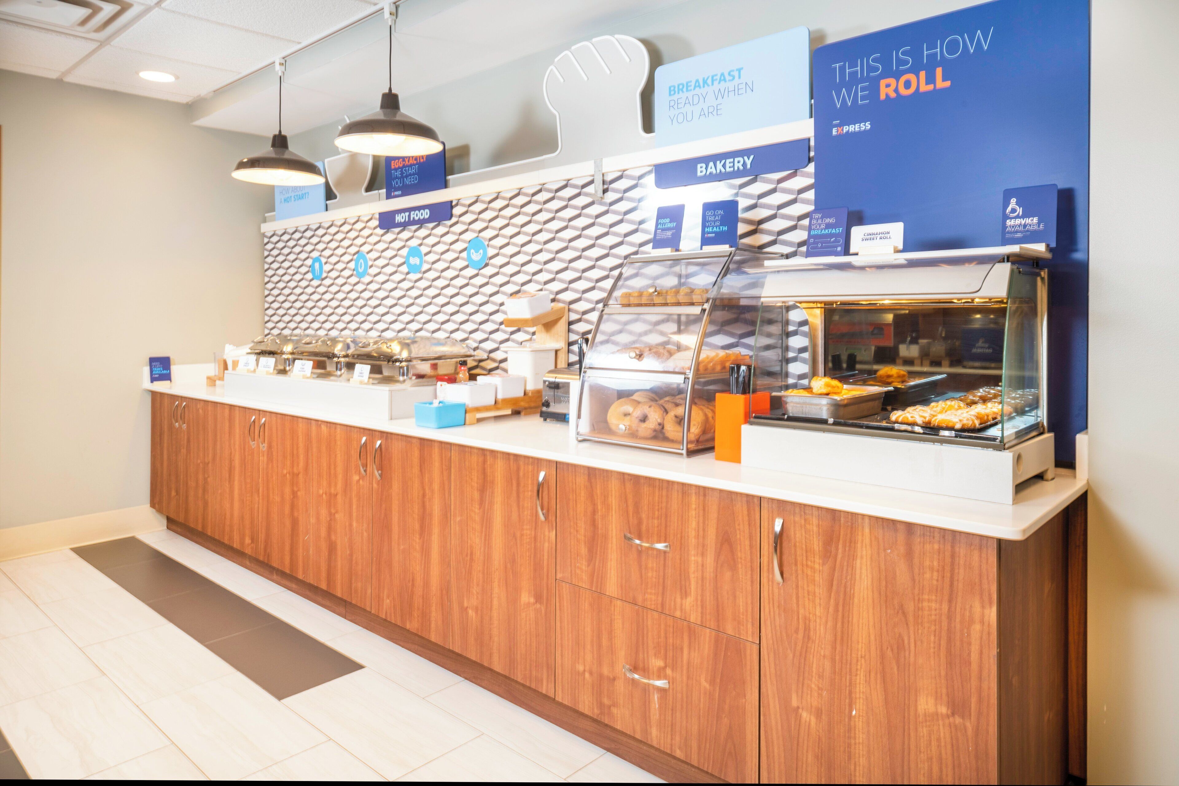 A bakery counter with various baked goods on display, a sign indicating the availability of service for guests with disabilities, and a sign promoting breakfast options.