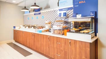 A bakery counter with various baked goods on display, a sign indicating the availability of service for guests with disabilities, and a sign promoting breakfast options.