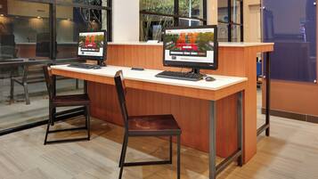 A reception desk with two computer monitors, a wooden counter, and a single chair.