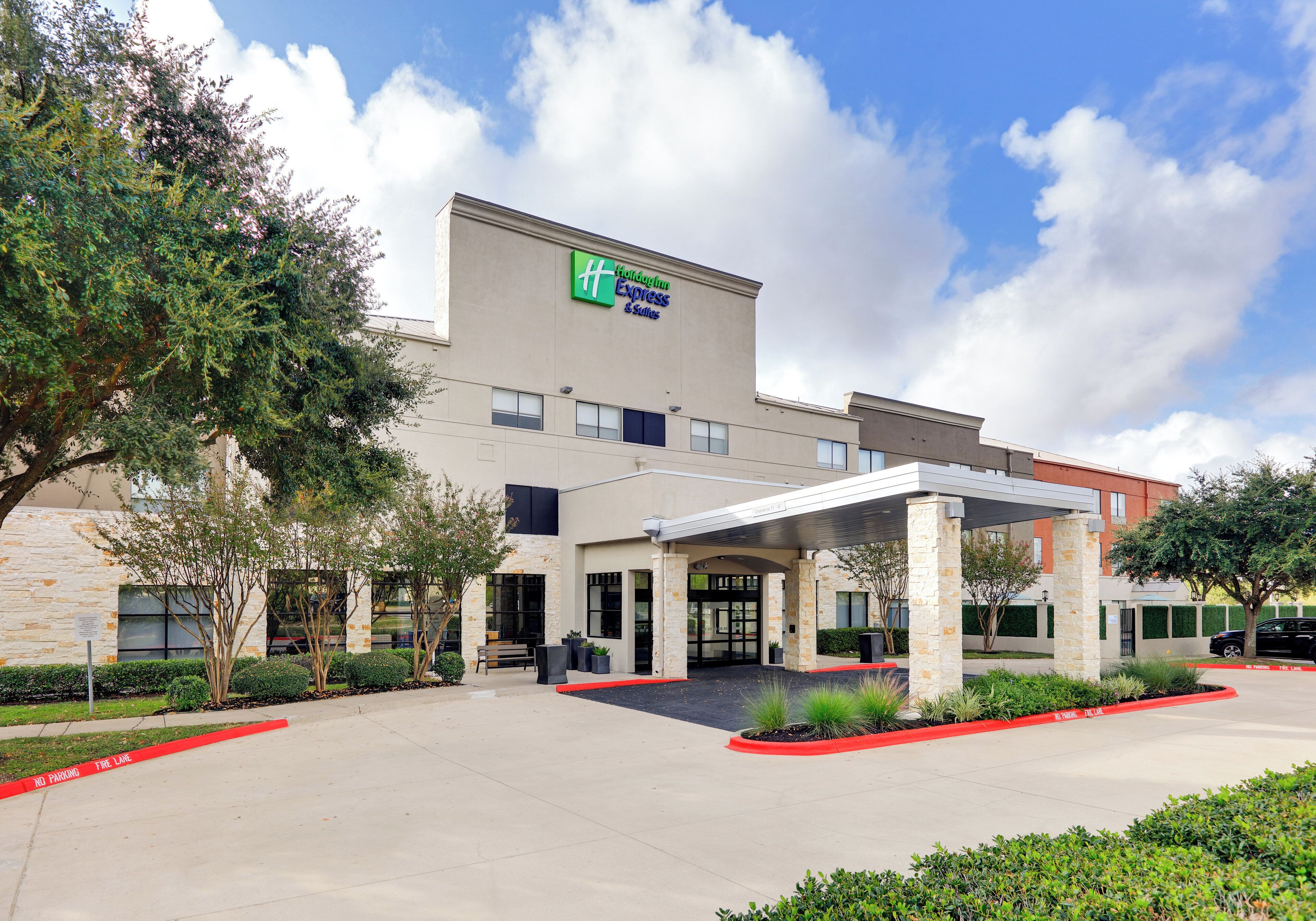 A Holiday Inn Express & Suites building with a covered entrance and a parking lot.