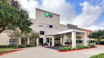 A Holiday Inn Express & Suites building with a covered entrance and a parking lot.