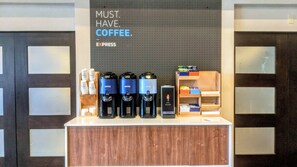 A coffee station with multiple coffee dispensers, a sign stating "MUST HAVE COFFEE", and a shelf with coffee pods. - Holiday Inn Express & Suites Austin Round Rock by IHG (Round Rock)