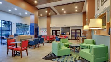 Relax in a spacious lobby with comfortable seating, a large rug, and artwork on the walls.
