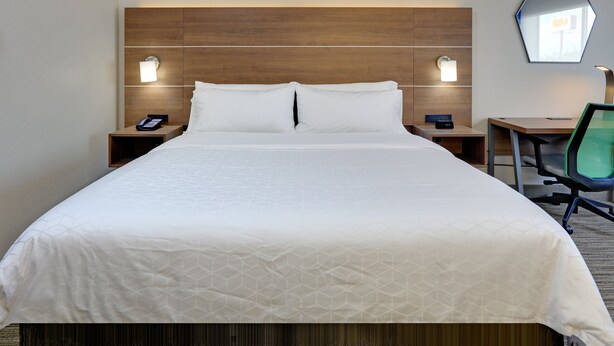A hotel room with a large bed, two bedside tables with lamps, a desk with a chair, and a mirror on the wall. - Holiday Inn Express & Suites Austin Round Rock by IHG (Round Rock)