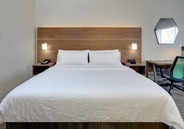 A hotel room with a large bed, two bedside tables with lamps, a desk with a chair, and a mirror on the wall. - Holiday Inn Express & Suites Austin Round Rock by IHG (Round Rock)