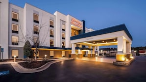Un hôtel Hampton Inn & Suites avec une enseigne bien visible, mesurant 13 pieds et 6 pouces de haut, une architecture moderne et un hall d’entrée bien éclairé.