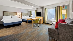 Une chambre d’hôtel avec deux lits, un bureau, une chaise, un canapé et une télévision.