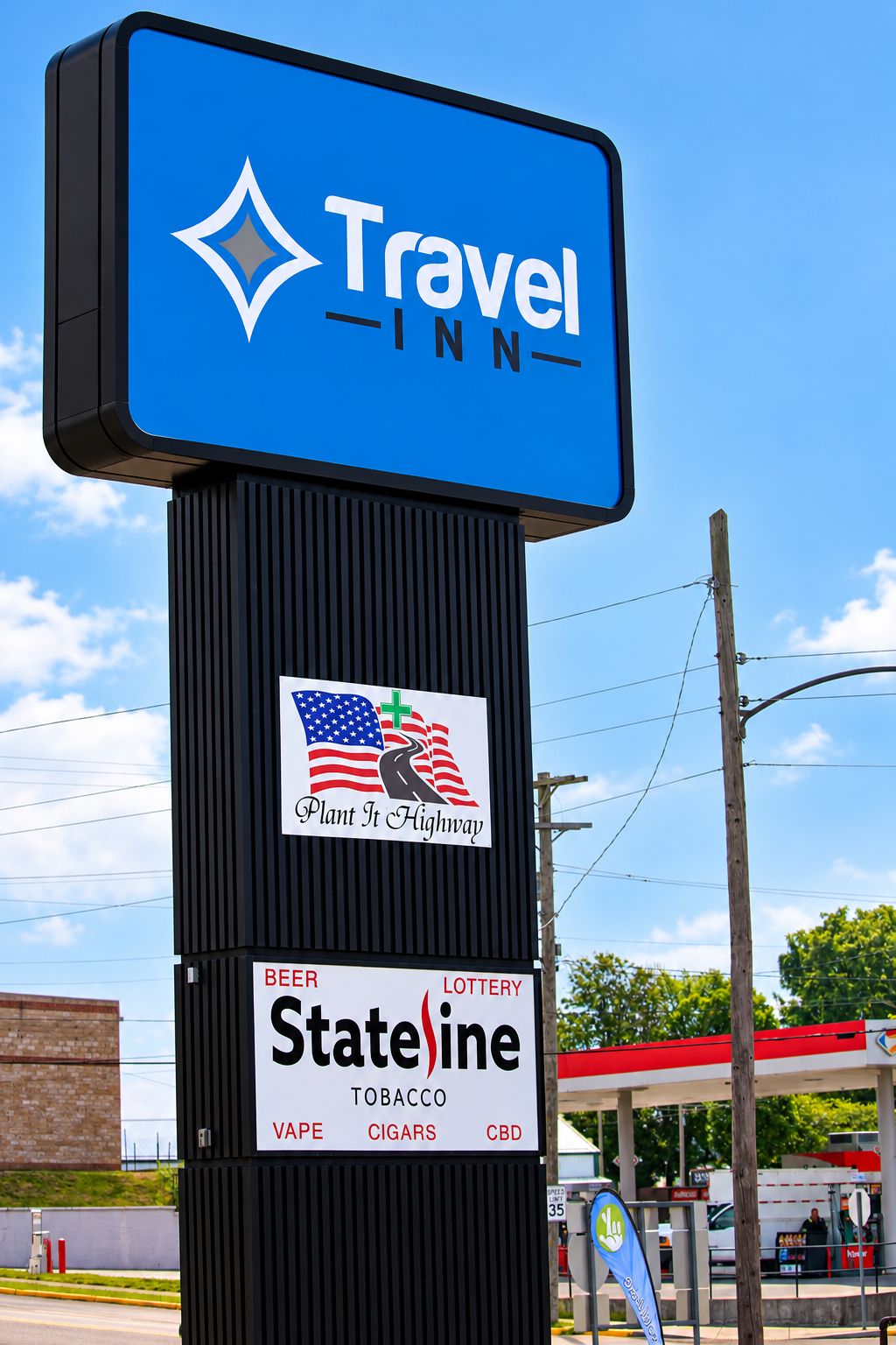 A Travel Inn sign with a logo, a 'Plant It Highway' logo, and a StateLine sign advertising beer, lottery, tobacco, vape, cigars, and CBD.