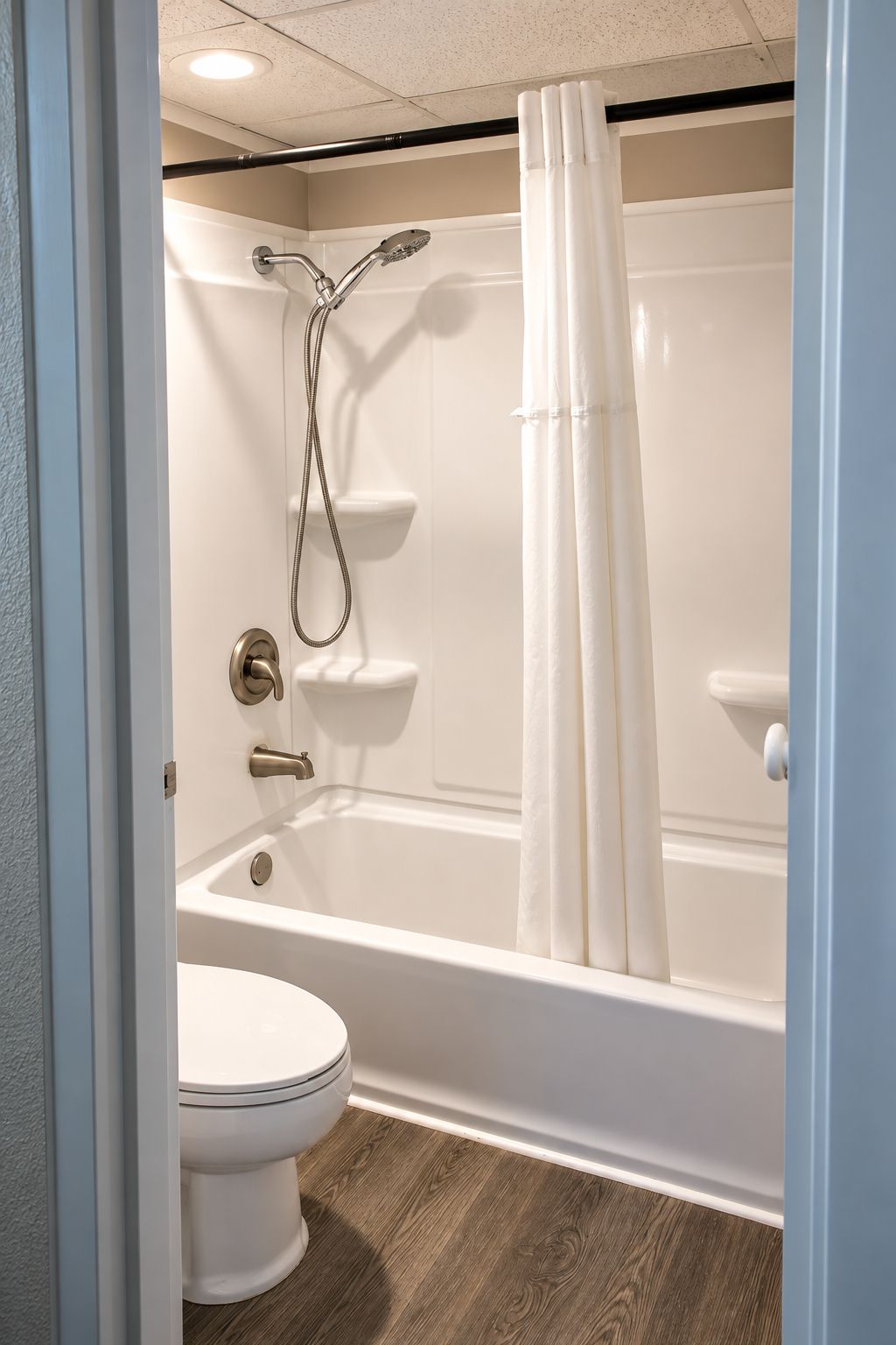 A bathroom with a white bathtub, a showerhead, and a toilet.