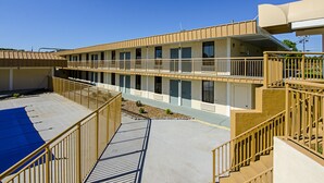 A multi-story motel with a central courtyard, balconies, and a covered parking area. - Travel Inn Bristol near State St (Bristol)
