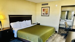 A hotel room with a bed, a nightstand, a lamp, a framed picture on the wall, and a bathroom visible through an open door. - Travel Inn Bristol near State St (Bristol)