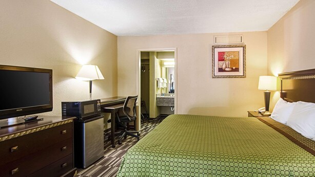 A hotel room with a bed, a desk, a television, and a bathroom visible through an open door. - Travel Inn Bristol near State St (Bristol)