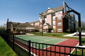 A multi-story residential building with a basketball court in front.