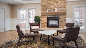 A living room with a stone fireplace, four armchairs, a coffee table, and a patterned rug. - Residence Inn by Marriott Poughkeepsie (Poughkeepsie)