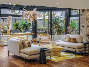 Una sala de estar moderna con un sofá, sillones, una mesa de centro y un comedor con sillas y una mesa.