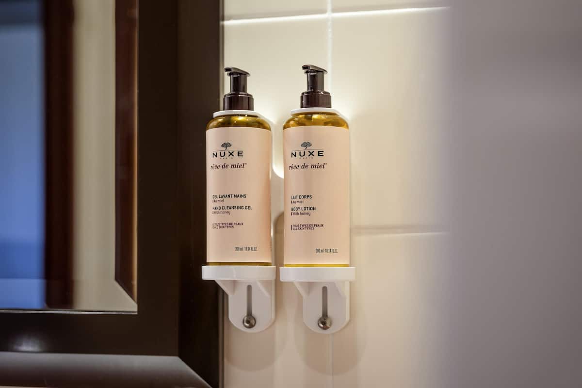 Two Nuxe Paris hand cleansing gel bottles mounted on a wall.