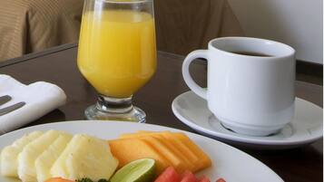 Un desayuno con un plato de comida, un vaso de zumo de naranja y una taza de café sobre una mesa.