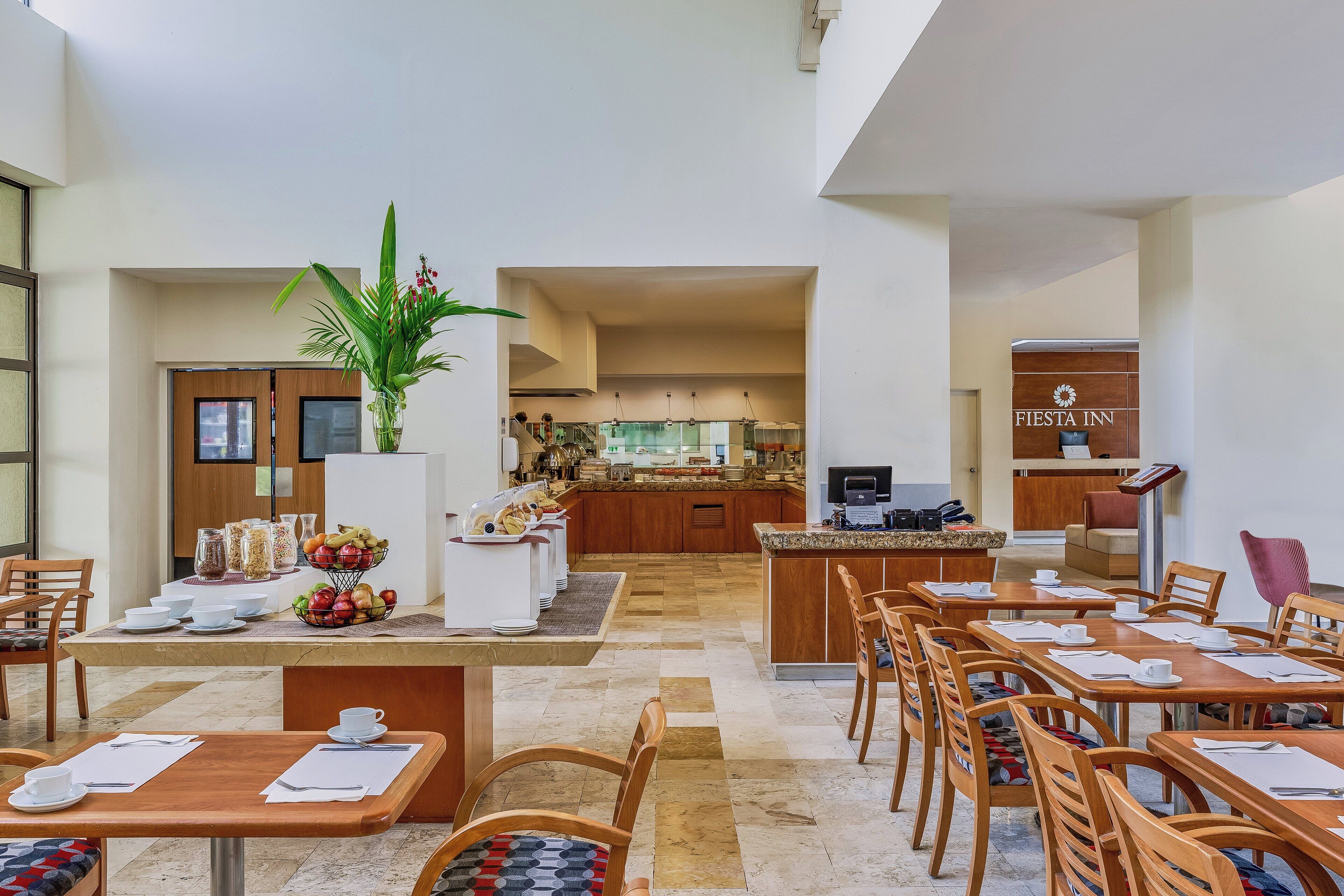 A hotel lobby with a dining area, a kitchen, and a reception desk.