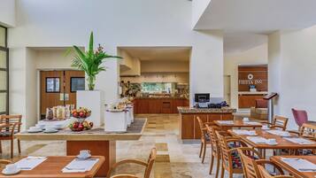 A hotel lobby with a dining area, a kitchen, and a reception desk.