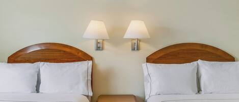 A double bed with white bedding, two bedside tables with lamps, and wooden headboards.
