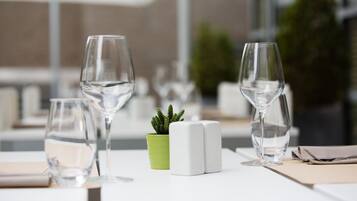 Uma mesa com três copos de vinho, um pequeno vaso de planta, saleiro e pimenteiro, e um guardanapo.