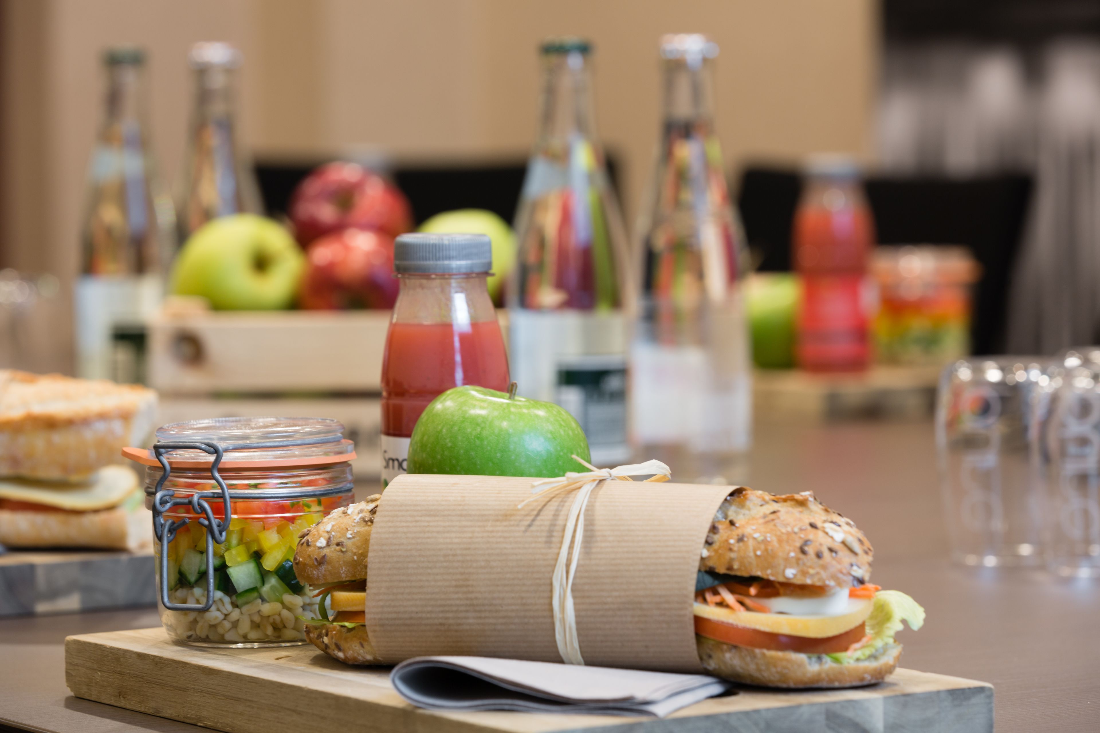 A table with sandwiches, a jar of pickles, and bottles of drinks.