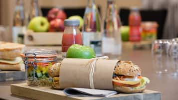A table with sandwiches, a jar of pickles, and bottles of drinks.