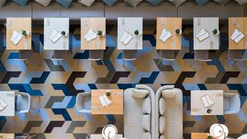A modern hotel lobby with multiple seating areas, including sofas and tables, arranged in a geometric pattern.