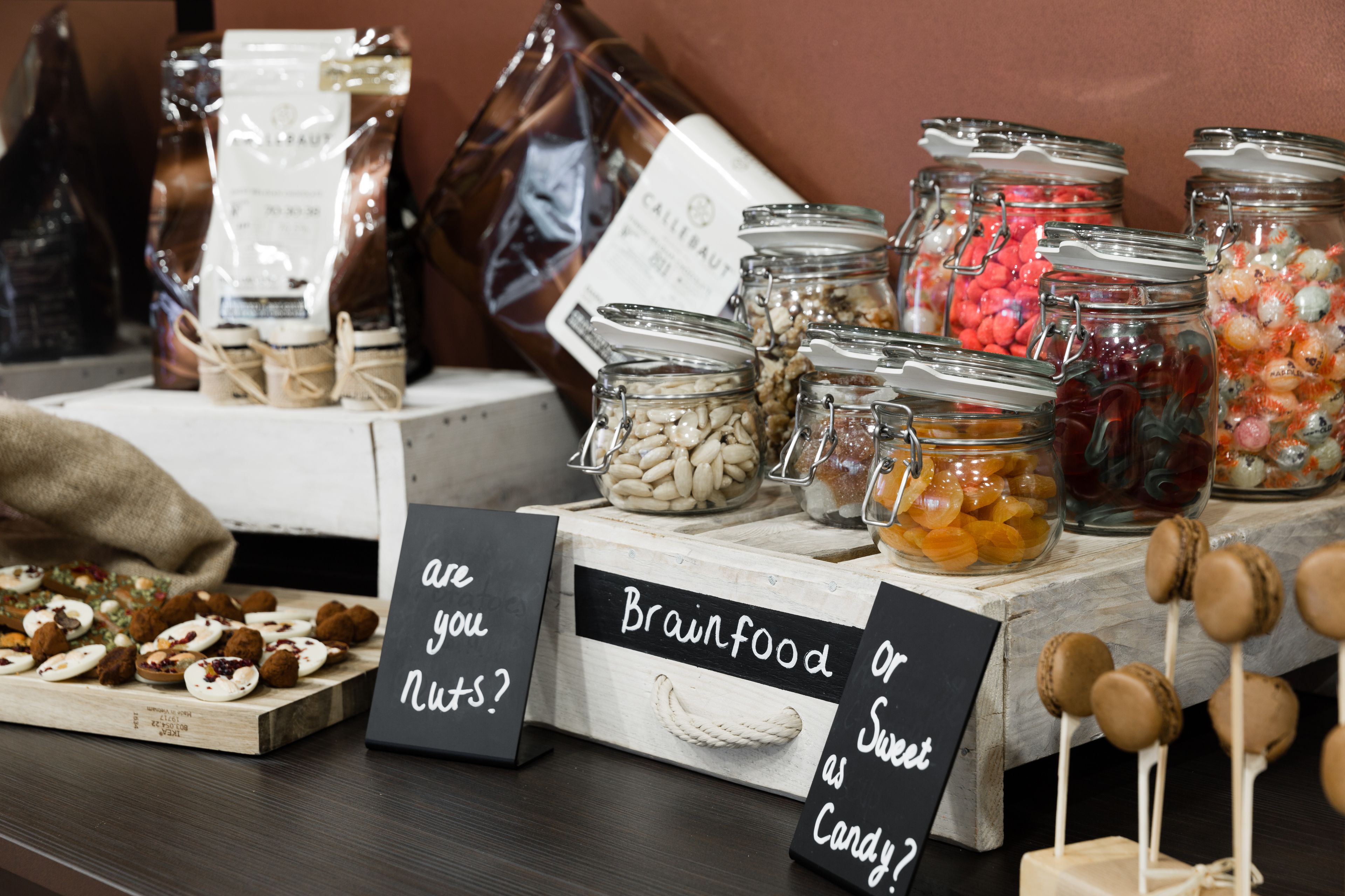 A display of various jars containing different types of food items, with signs asking if the viewer considers them nuts or sweet as candy.