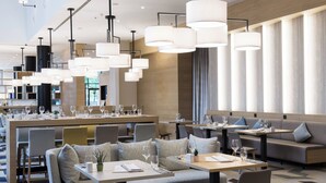 A modern restaurant with multiple seating areas, including booths and tables, and pendant lighting. - Courtyard by Marriott Brussels (Brussels)