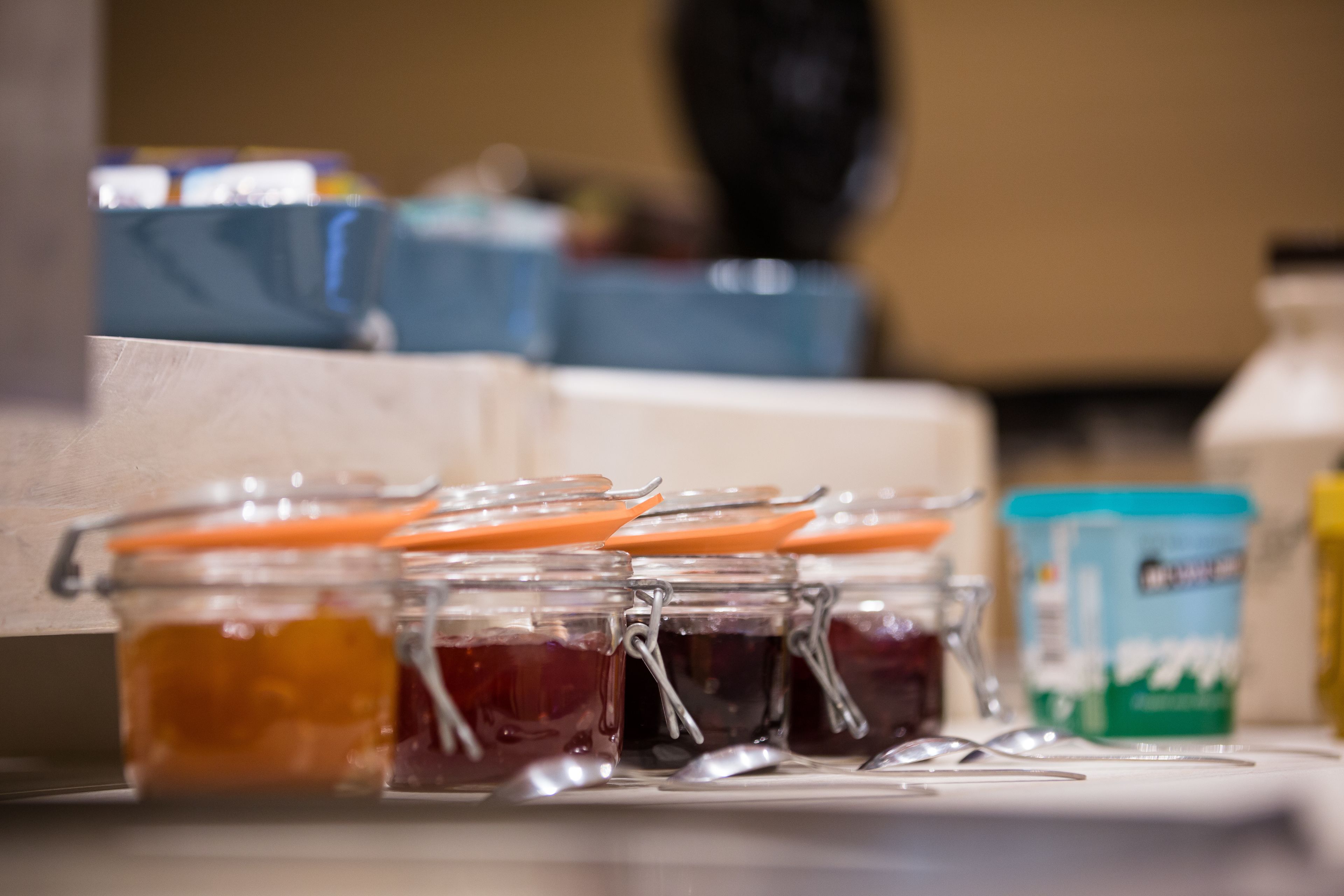 A kitchen counter with jars of preserves and a container of yogurt.