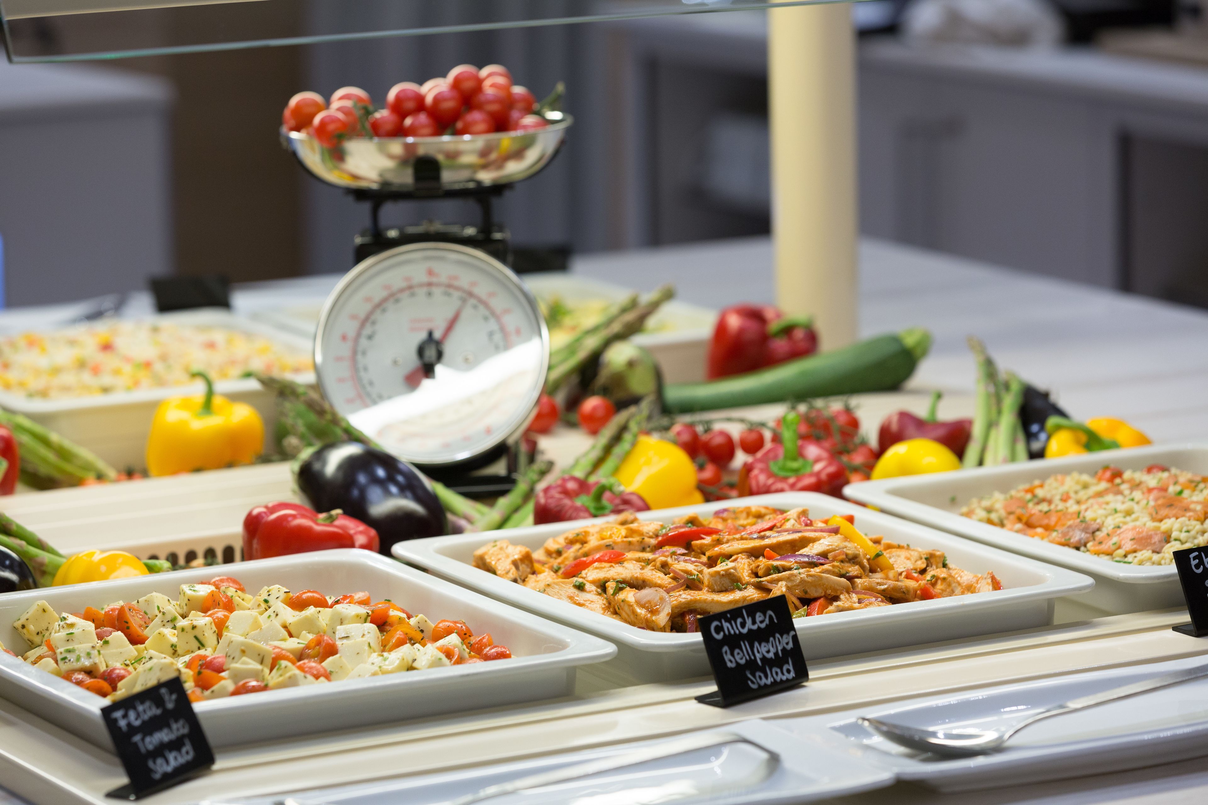 A buffet with various dishes including chicken bell pepper salad, feta tomato salad, and rice with salmon.