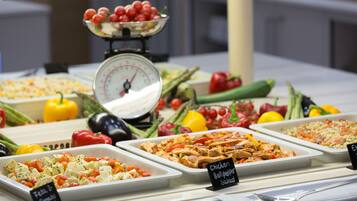 A buffet with various dishes including chicken bell pepper salad, feta tomato salad, and rice with salmon.