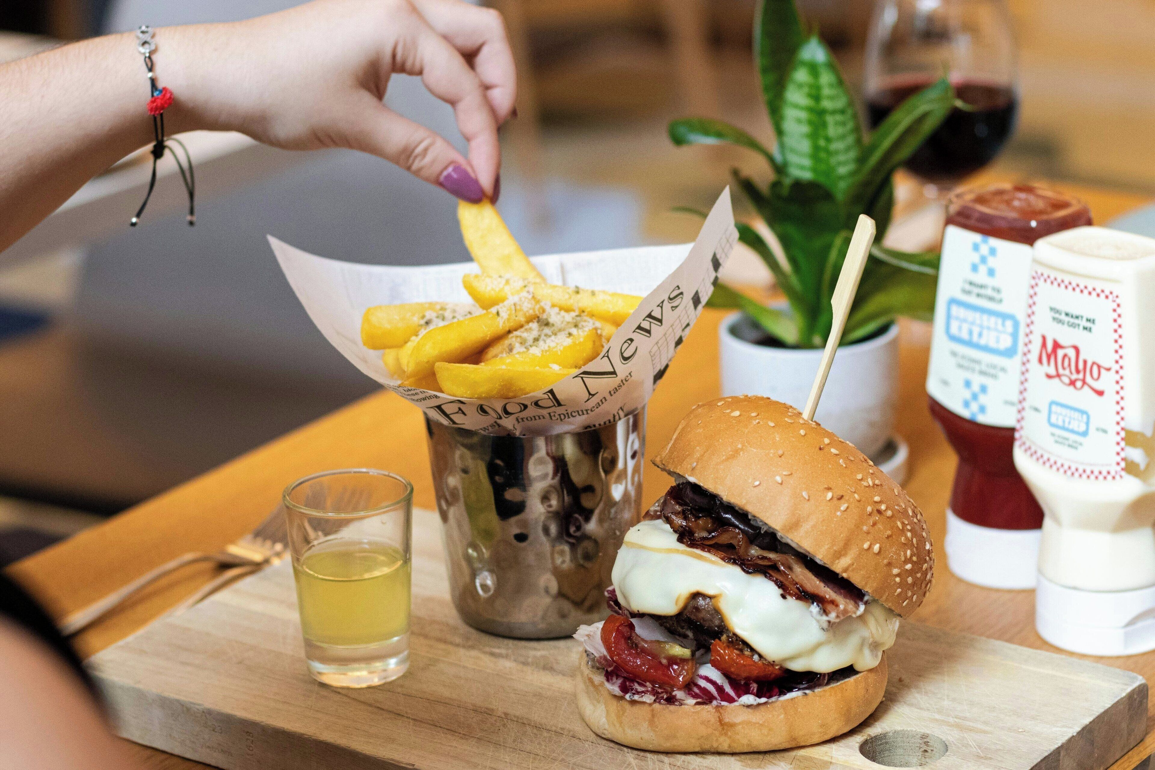 A meal with a burger, fries, and a drink on a wooden table.