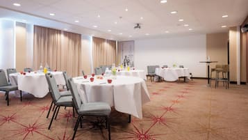 A conference room with round tables, chairs, and a carpeted floor.