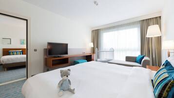 Una habitación de hotel con una cama grande, televisor, escritorio y una silla.