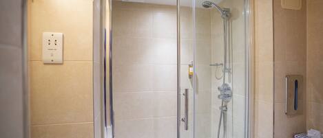 A modern shower with a glass door, a handheld showerhead, and a wall-mounted control panel.